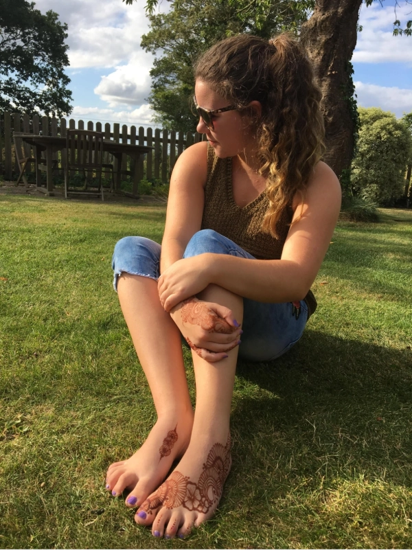 Henna artist sat in garden with henna on hands and feet